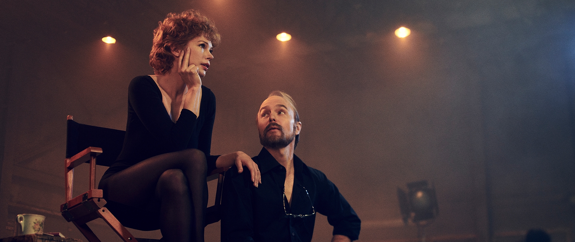 Sam Rockwell as Bob Fosse, Michelle Williams as Gwen, sitting in a theatre stage setting in black dance attire.
