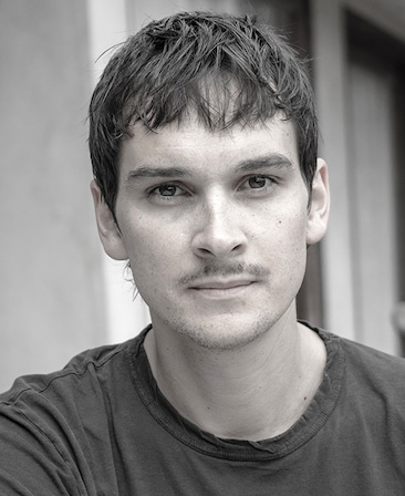 Headshot of Joseph Baken, Executive Producer of FX's Grotesquerie, in black and white, wearing a t-shirt.