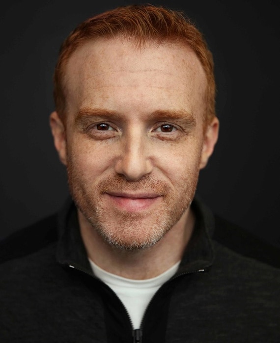 Jonathan E. Steinberg headshot wearing a white shirt with a black jacket over
