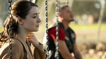 Emily and JD sitting on a swing set outside