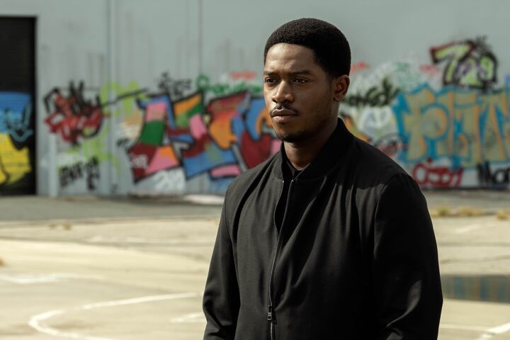 Damson Idris as Franklin Saint standing outside in front of graffiti on concrete
