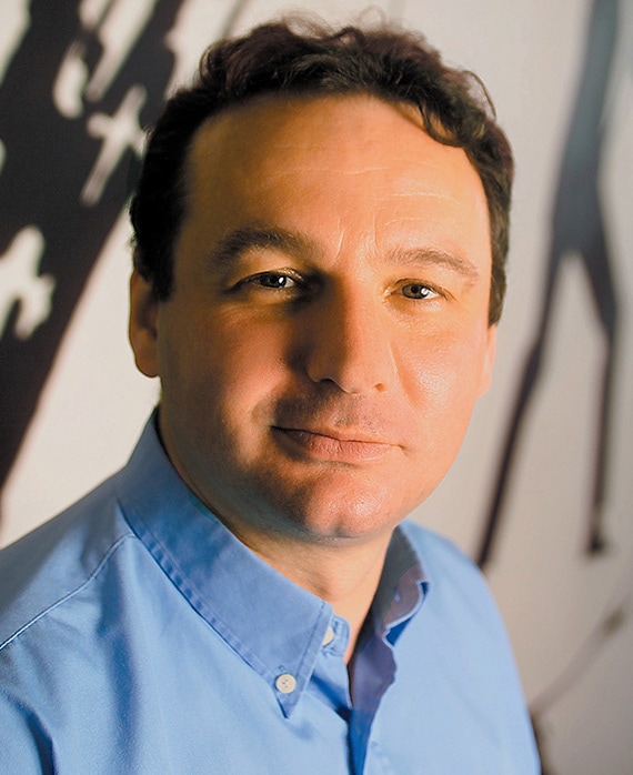 Jon Thoday headshot in light blue button down with bright light shining on half of his face, with black and white background