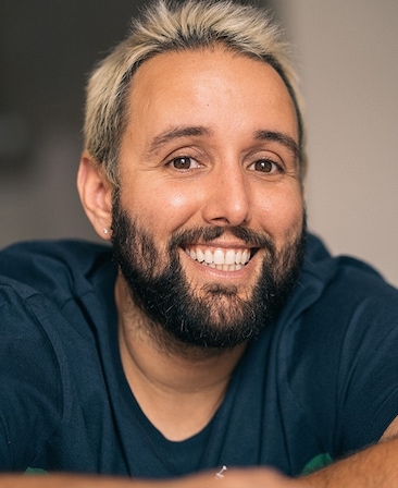 Headshot of executive producer of FX's Necaxa, Alex Fumero, wearing a blue shirt and frosted tip hair.