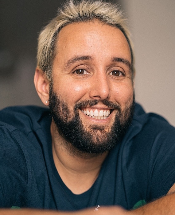 Headshot of executive producer of FX's Necaxa, Alex Fumero, wearing a blue shirt and frosted tip hair.
