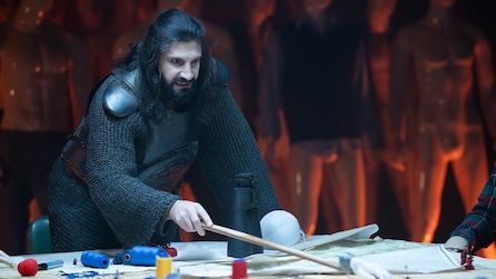 Kayvan Novak as Nandor the Relentless in FX's What We Do in the Shadows holding a stick, pointing it at a makeshift war table