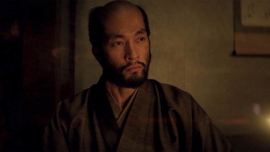 Close up of Buntaro sitting in Blackthorne's house lit by fire light