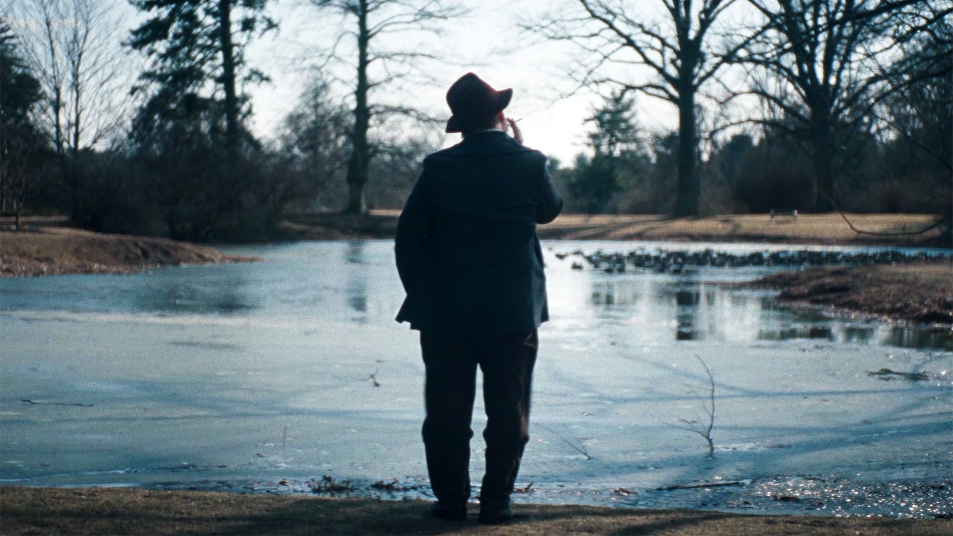 Truman Capote facing a lake with his back turned to the camera.