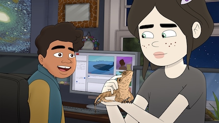 Chrissy Feinberg in grey shirt holding brown reptile with both hands with friend looking at her in FX's Little Demon