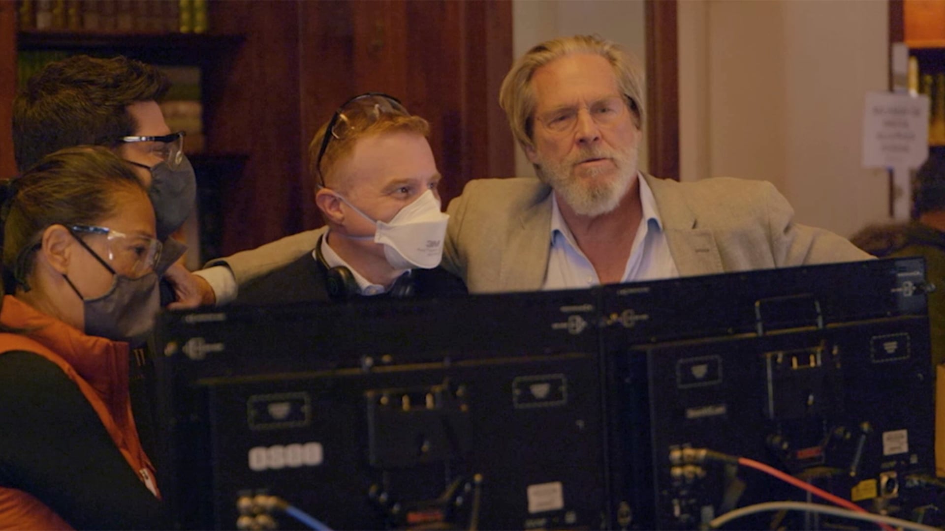 Jeff Bridges wrapping his arm around a crew member standing behind computers