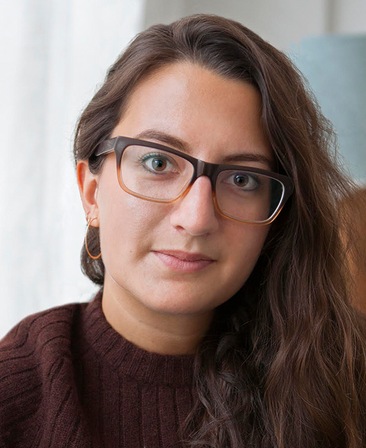 Sarina Roma headshot wearing a burgundy sweater and glasses