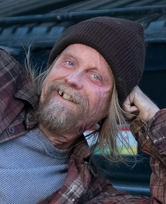 David Hornsby headshot laying down with his hand on his head, wearing a brown flannel and a black beanie