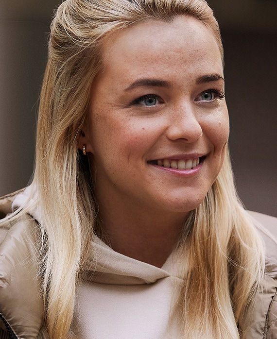 Jessie Williams headshot wearing a light pink hoodie and puffer jacket.