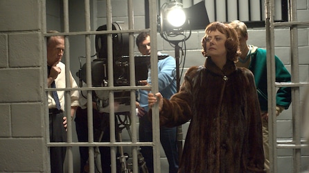 Susan Sarandon as Bette Davis shooting scene inside white jail cell wearing brown fur coat in Feud FX show