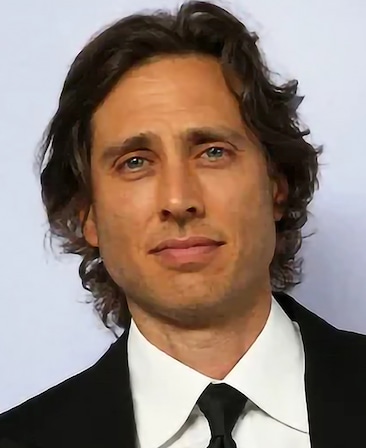 Brad Falchuk headshot wearing a black suit with white shirt standing against a while background