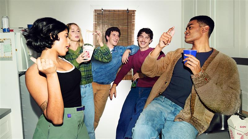 A group of 5 friends smiling in a kitchen together.