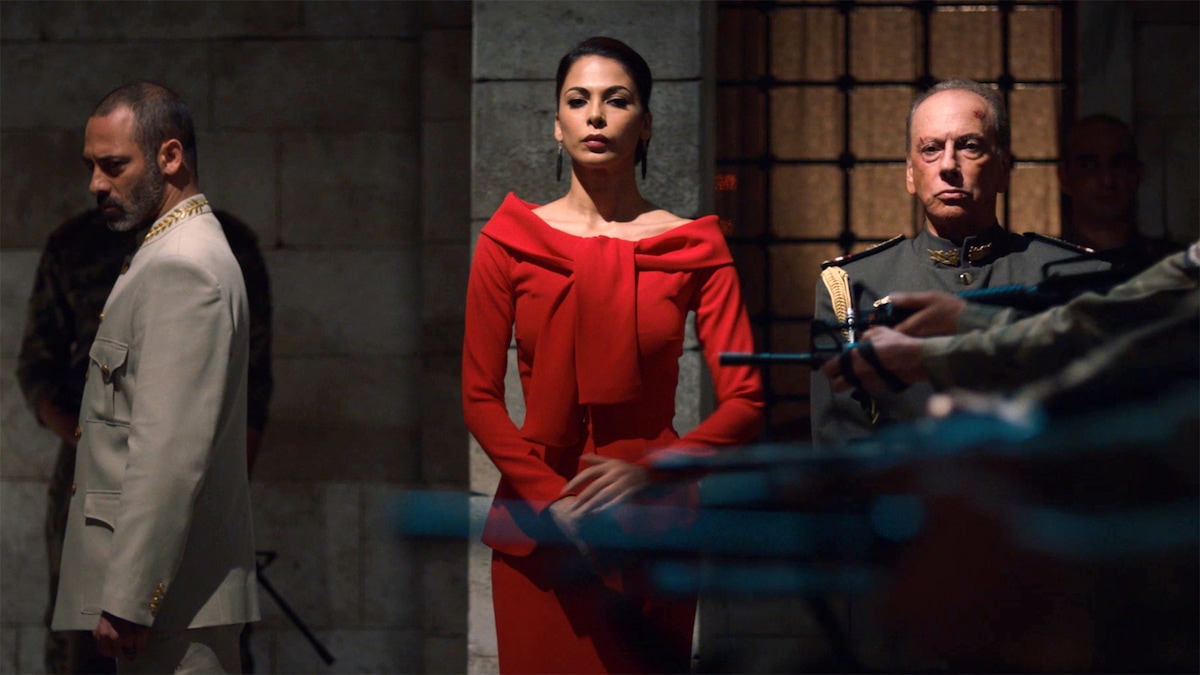 Woman standing in a red dress in the middle of two other men in uniform