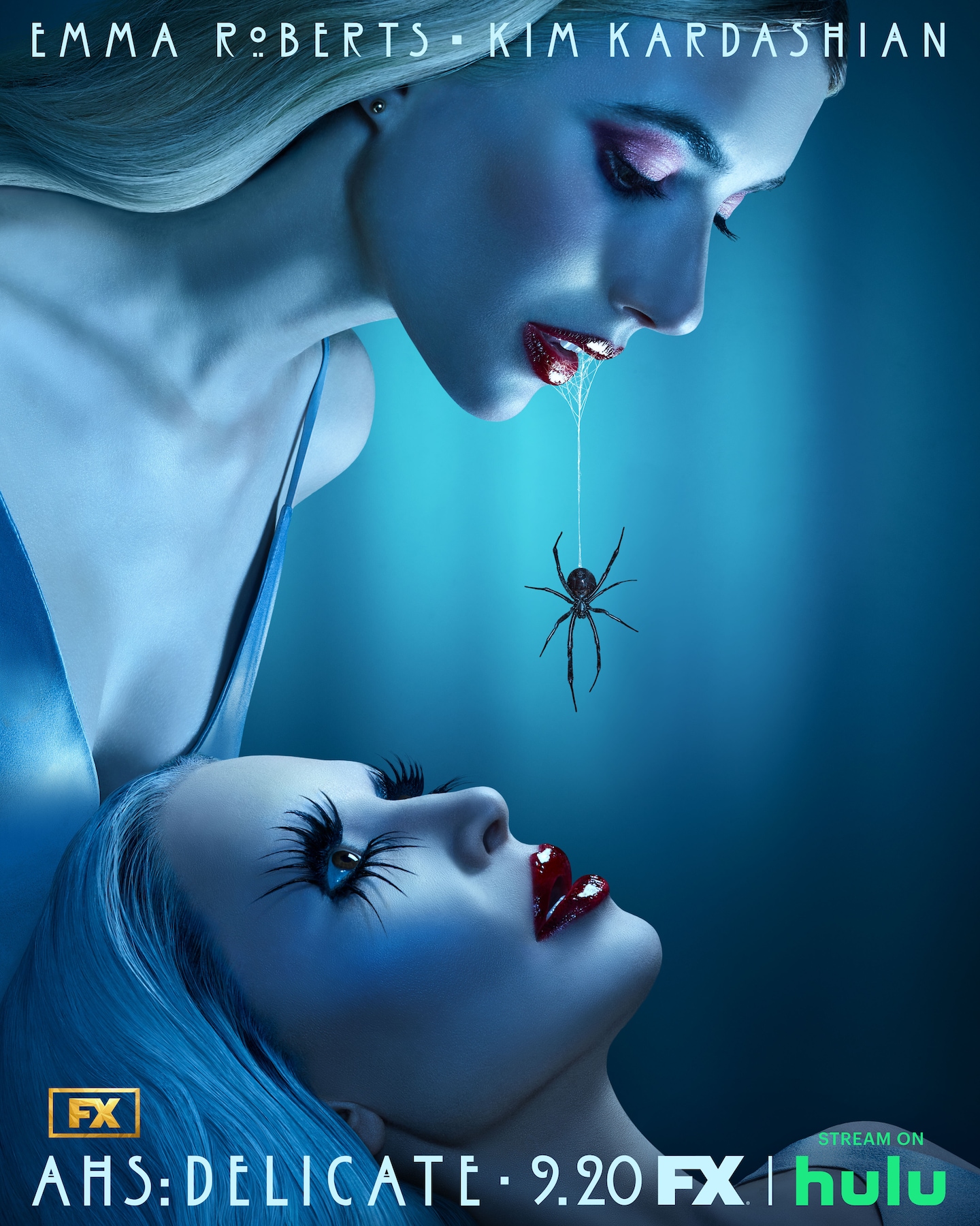 A pale woman hovers over another with a spider dangling from her red lips for AHS: Delicate