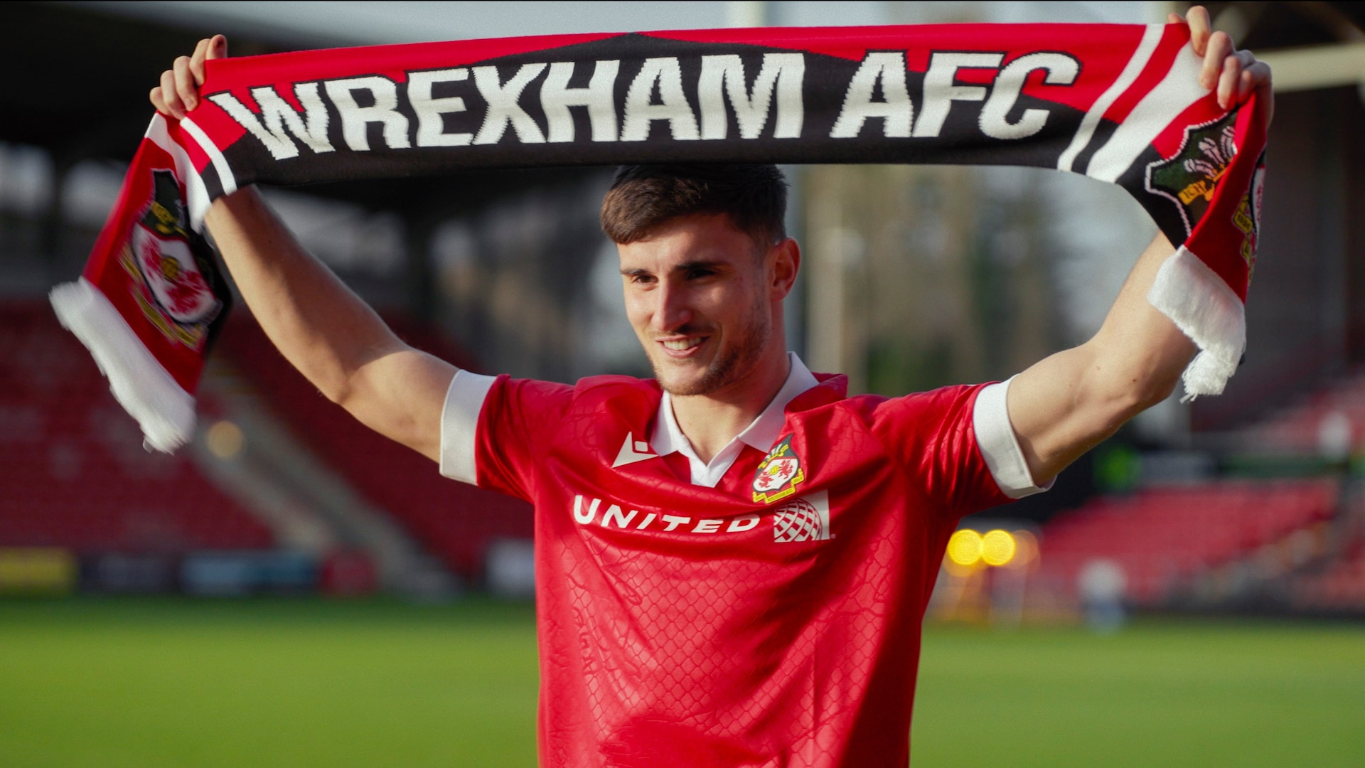 Wrexham player holding a banner over his head on the soccer field.