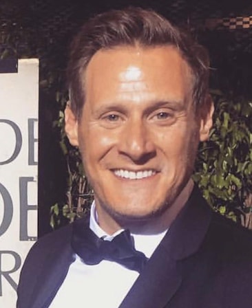 Trevor Engelson Headshot smiling and wearing a suit and bow tie