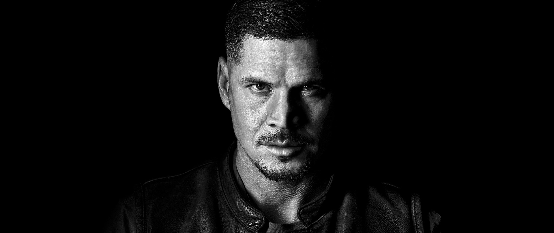 JD Pardo wearing a leather jacket with two badges that read Presidente and Mayans Santo Padre.