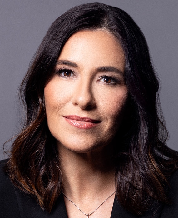 Headshot of Jen Sargent wearing a black suit, silver necklace with a light grey background behind her.
