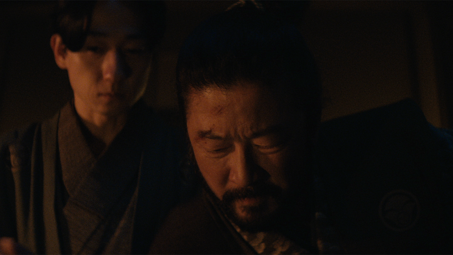 Yabushige writes his will by candle light as his kosho looks on