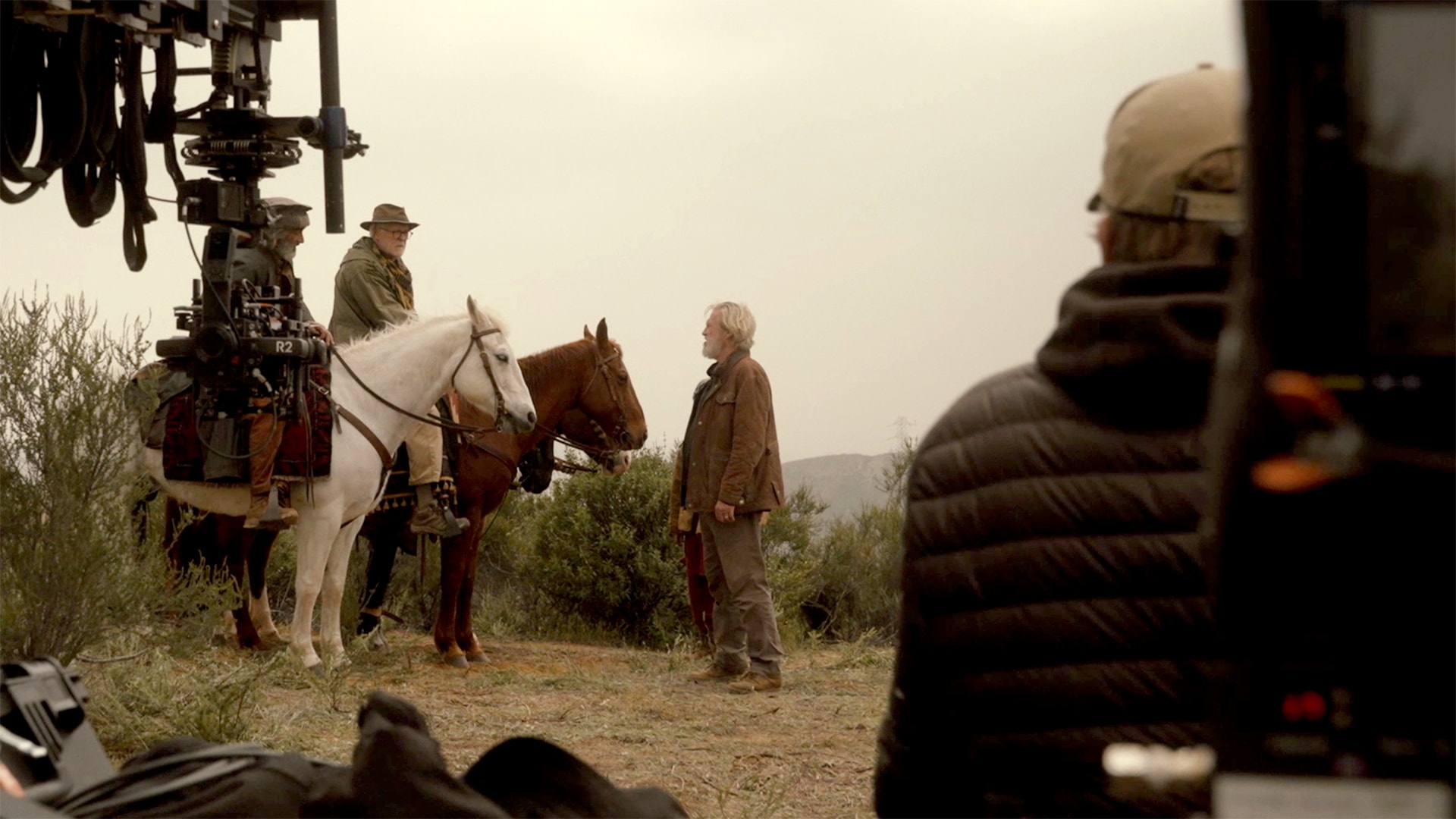 Jeff Bridges facing John Lithgow who is sitting on a brown horse next to Navid Negahban.