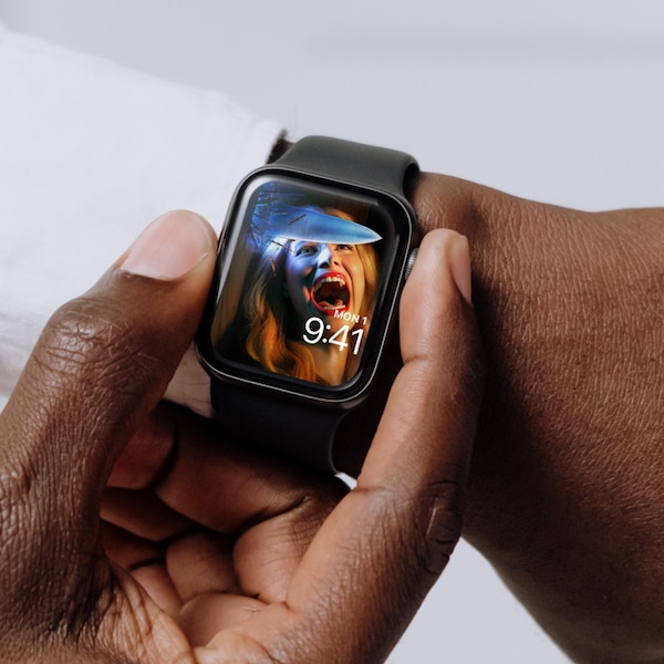 Man wearing Apple Watch with lock screen of a woman screaming with a knife piercing through the wall next to her head.