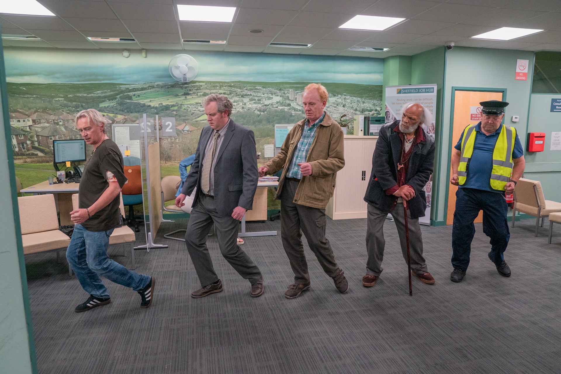 The Full Monty cast standing in a single file line