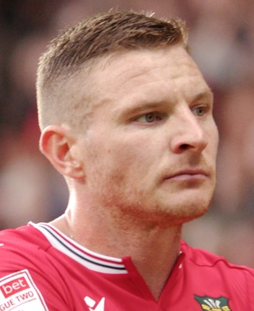 Paul Mullin headshot wearing a red shirt with a striped collar