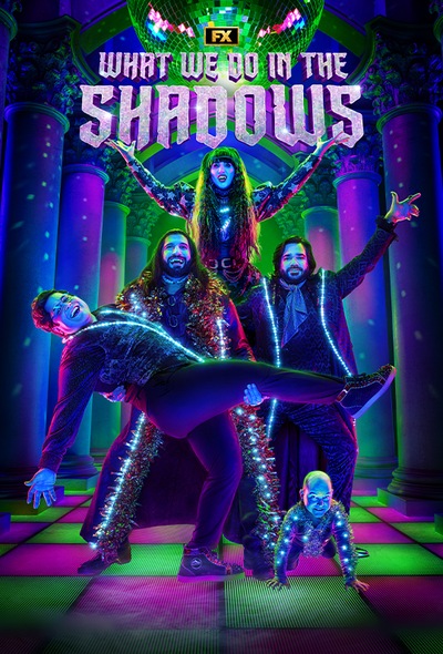 What We Do in the Shadows cast smiling with hands in the air on purple and green checkered floor with disco ball on ceiling