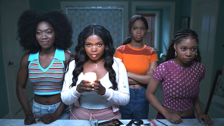 Four black women inside bathroom with colorful tops with one holding a candle in American Horror Stories Installment 2