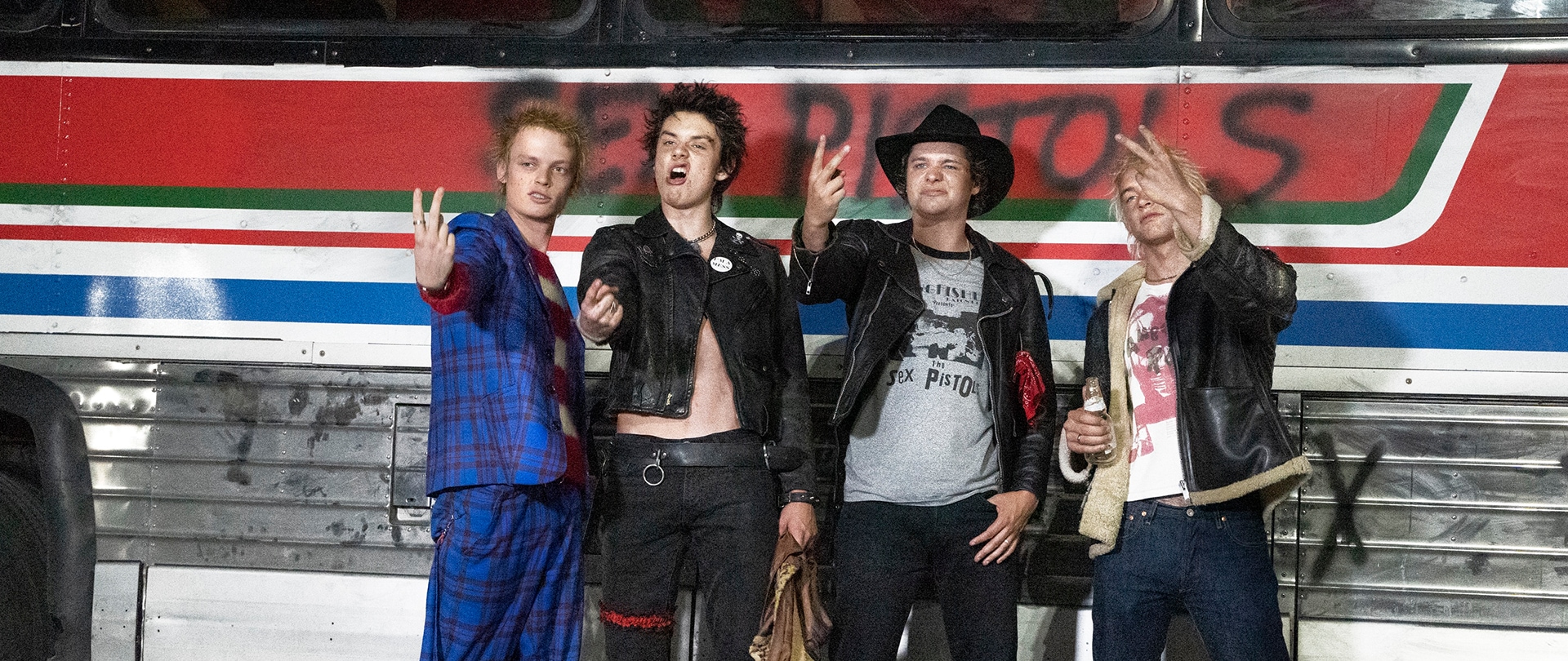 Cast of FX's Pistol standing in front of a blue and red graffitied bus.