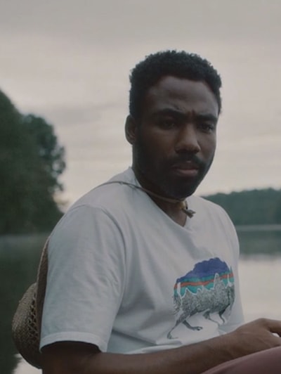 Earn from Atlanta FX show in a lake wearing a white shirt with straw hat tied around his neck looking confused