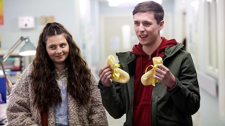 Luke holding up a pair of yellow baby socks and standing next to Ava