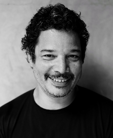 Headshot of Kevin Bray wearing a black shirt in a black and white filter.