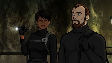 Zara and Algernop wearing black uniforms standing in a cave, as Zara holds a flashlight.