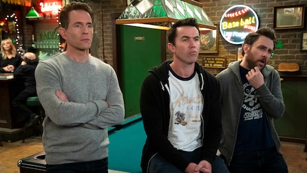 Dennis, Mac and Charlie leaning against a pool table, standing inside the bar.