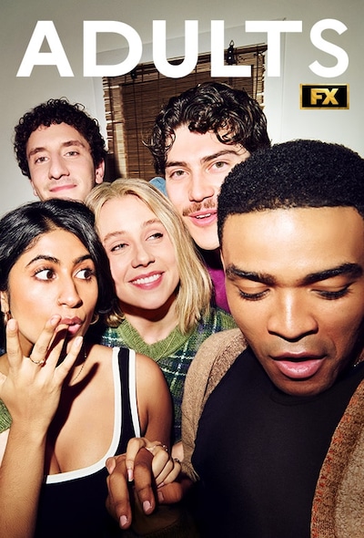 A group of five friends posing for a selfie while laughing in a small apartment kitchen.