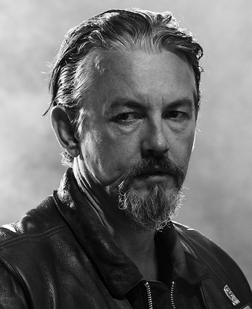 Tommy Flanagan headshot with combed back hair and wearing a leather jacket