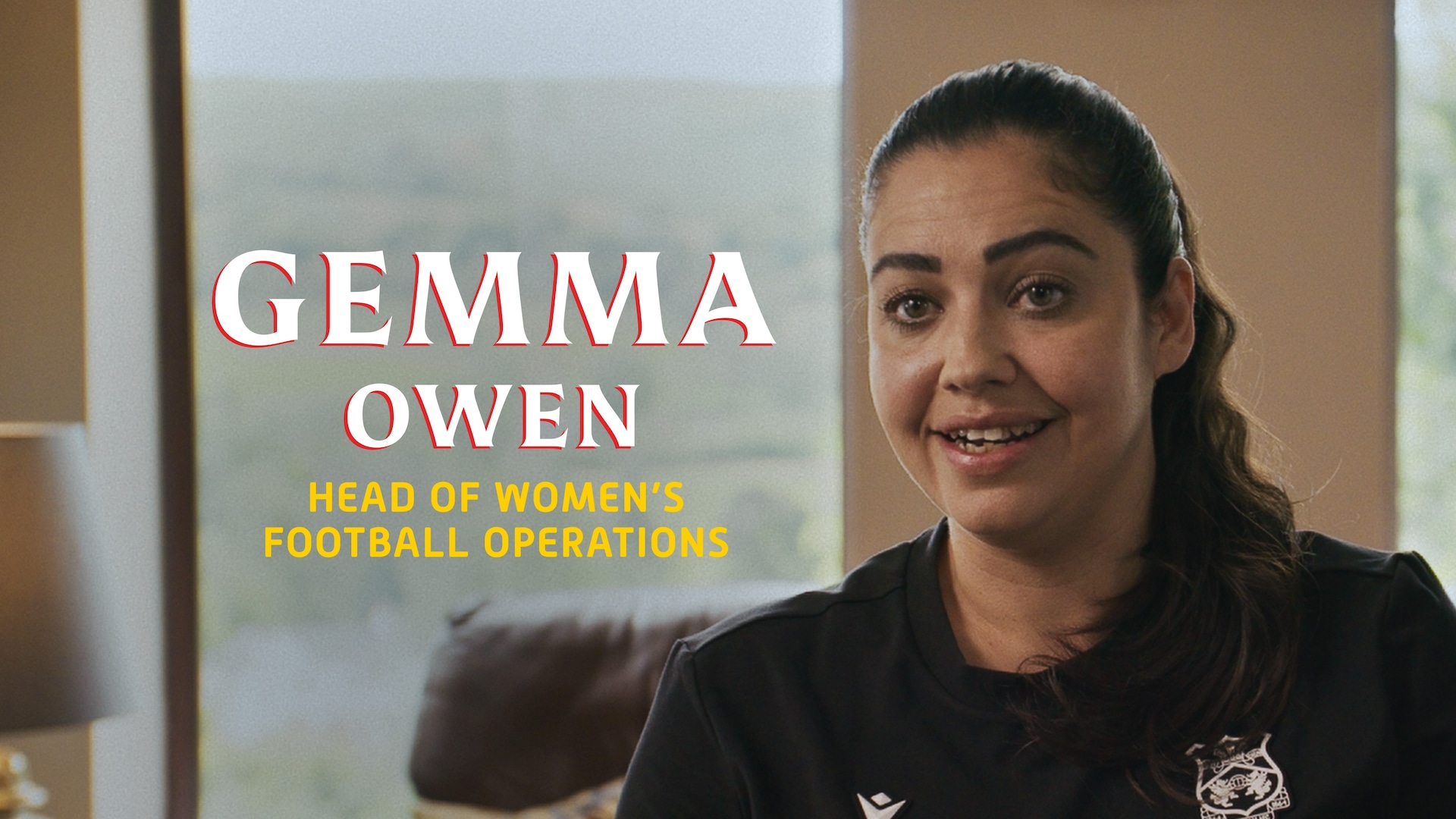 Gemma Owen headshot wearing a black zip up sitting in front of a window