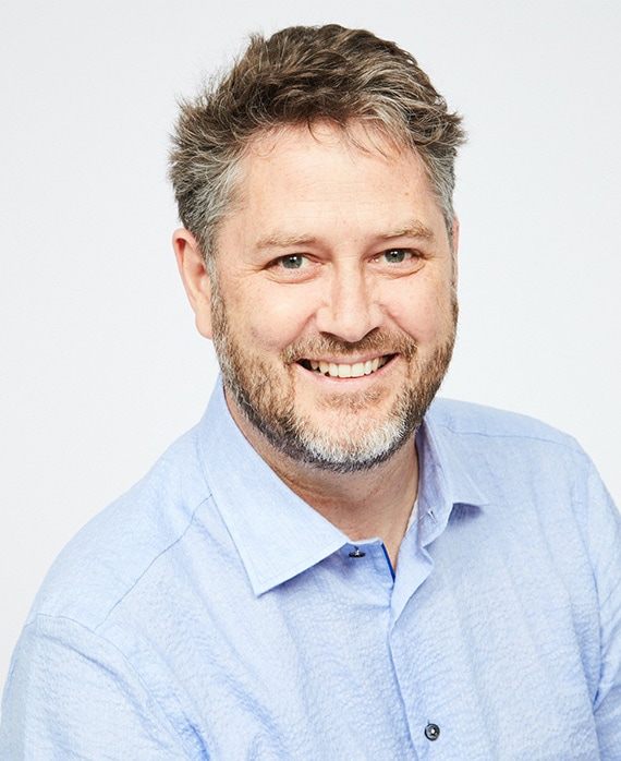 Headshot of Frank Evers in a blue button up and a white background.