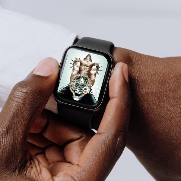 image 1 - Man wearing Apple Watch with lock screen of man with black pants and spikes on arms clenching spiked metal skull AH