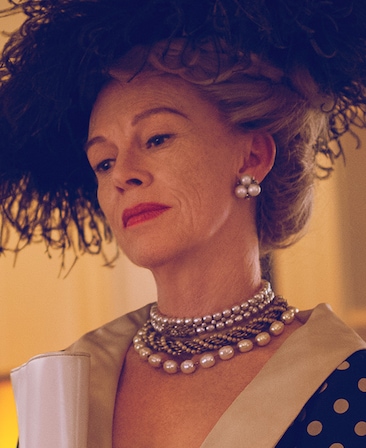 Judy Davis as Hedda Hopper wearing black fringe hat with polka dot dress and silver pearl jewelry in Feud FX show