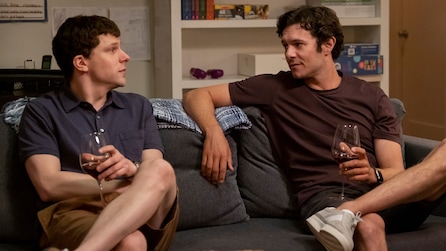 Jesse Eisenberg as Toby Fleishman drinking wine on couch with Adam Brody as Seth Morris in FX's Fleishman Is In Trouble