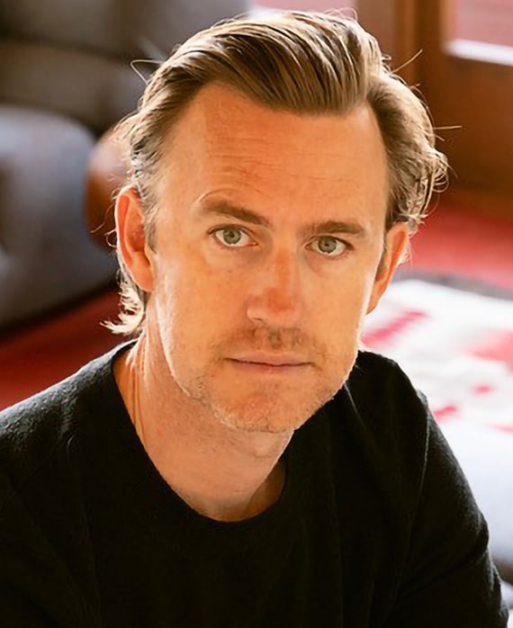 John J Gray headshot wearing a black shirt