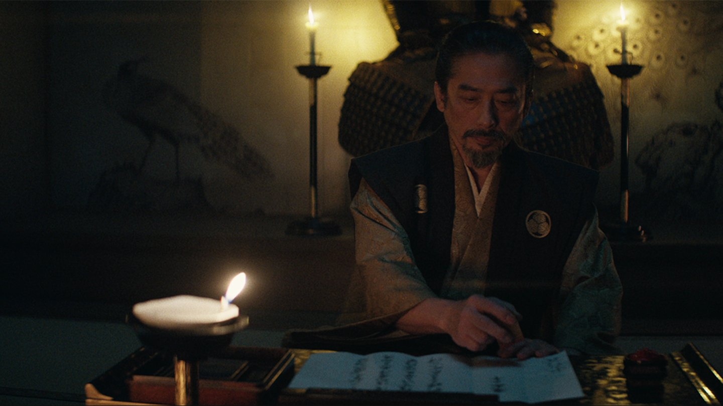 Lord Toranaga stamps a document in the West Palace at night