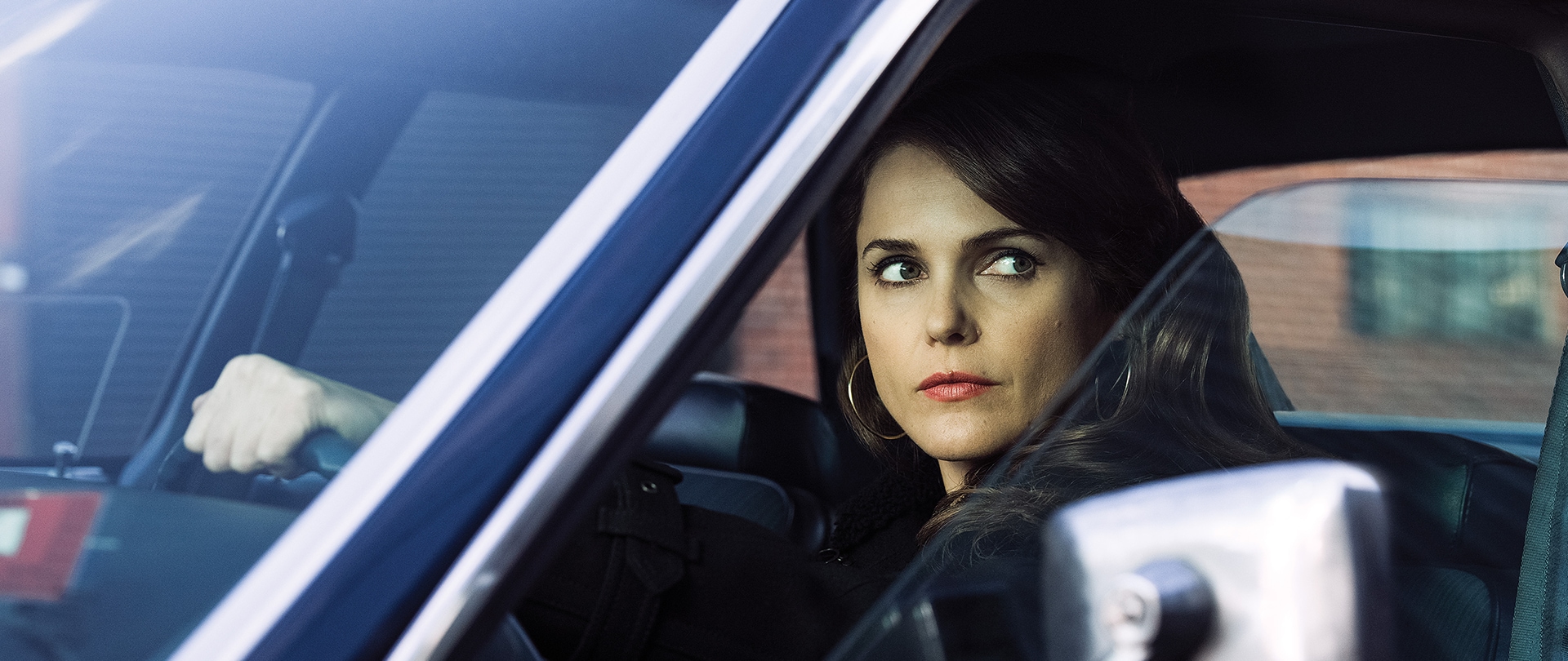 Keri Russell as Elizabeth Jennings in a blue car driving, looking out the window.
