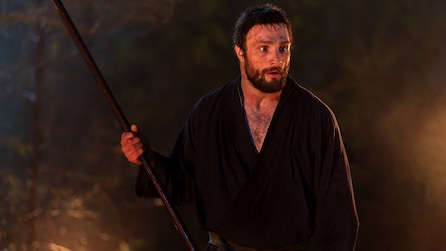 Close up of Blackthorne holding a long stick.