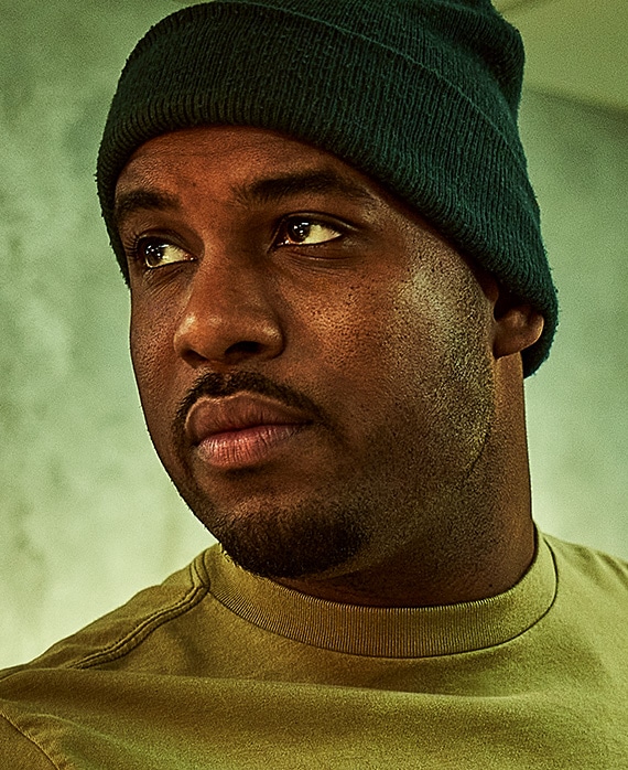 Lionel Boyce headshot wearing black beanie and green shirt